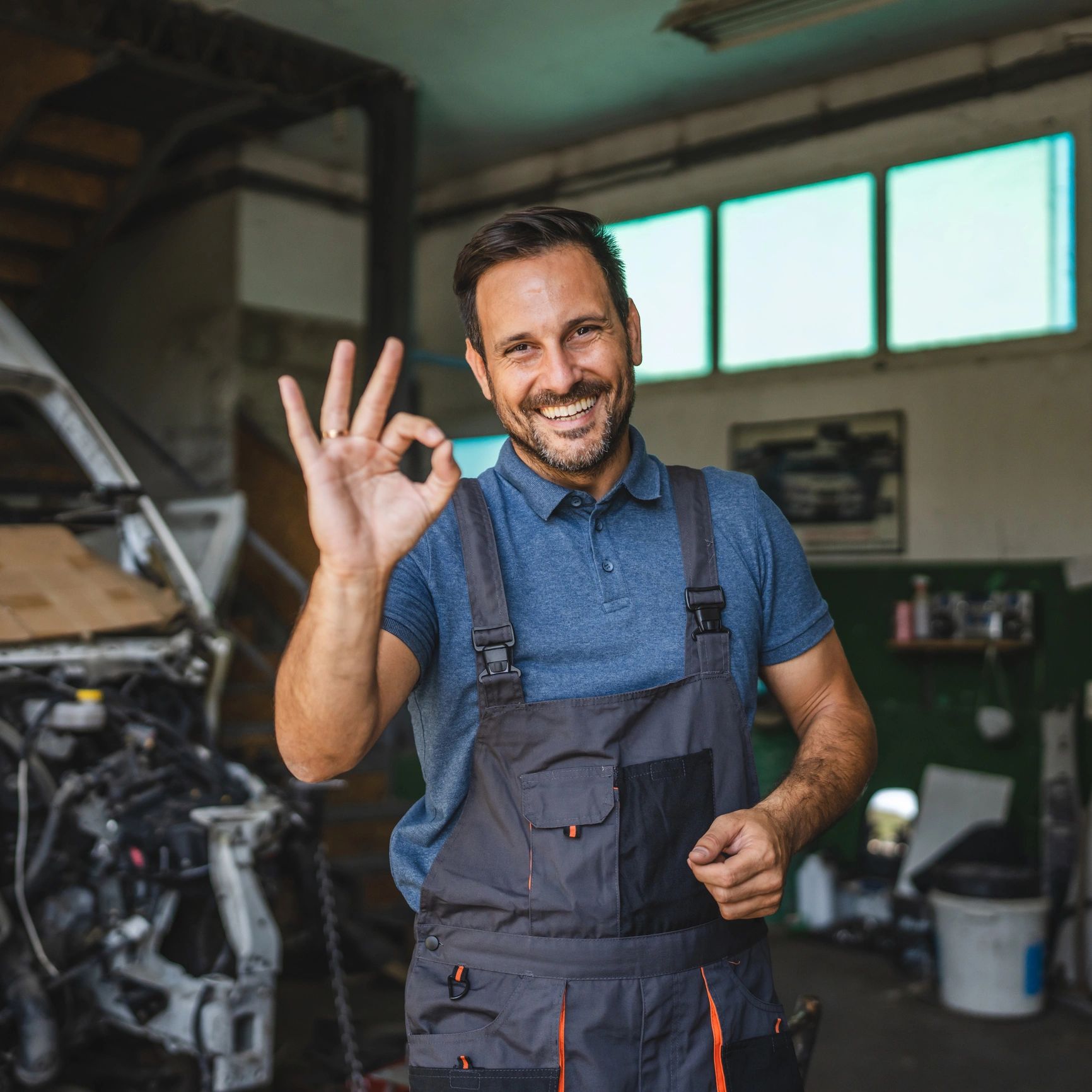 Smiling customer giving an OK sign near a car
