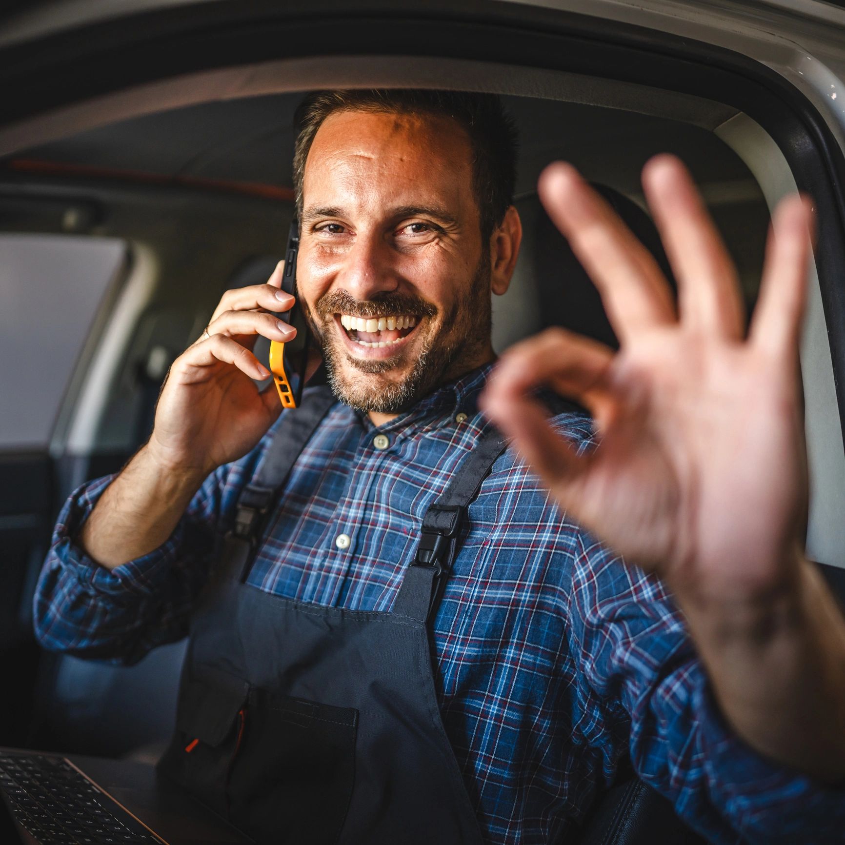 Smiling customer giving an OK sign inside a car