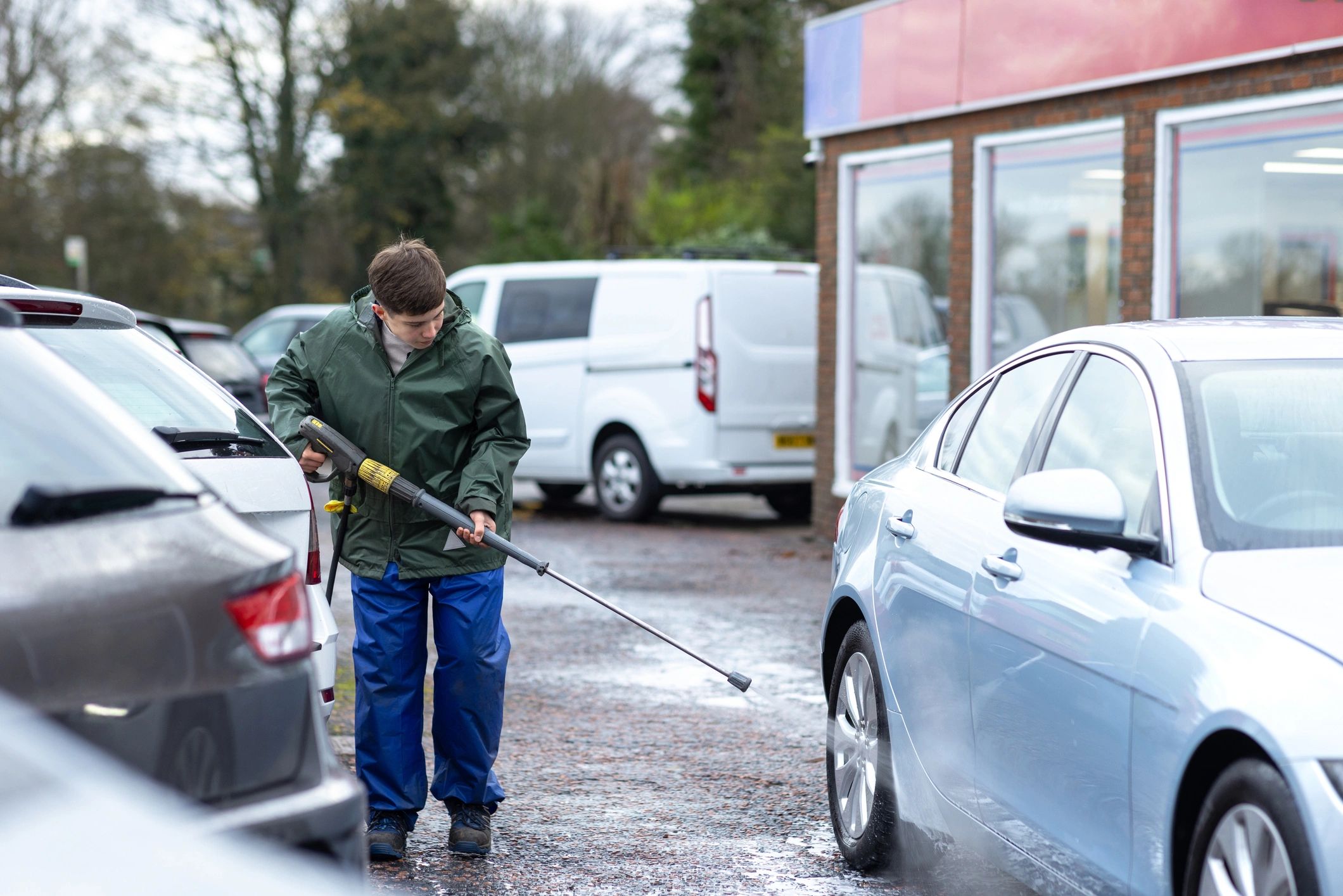 Mobile car wash technician cleaning wheels at a customer location