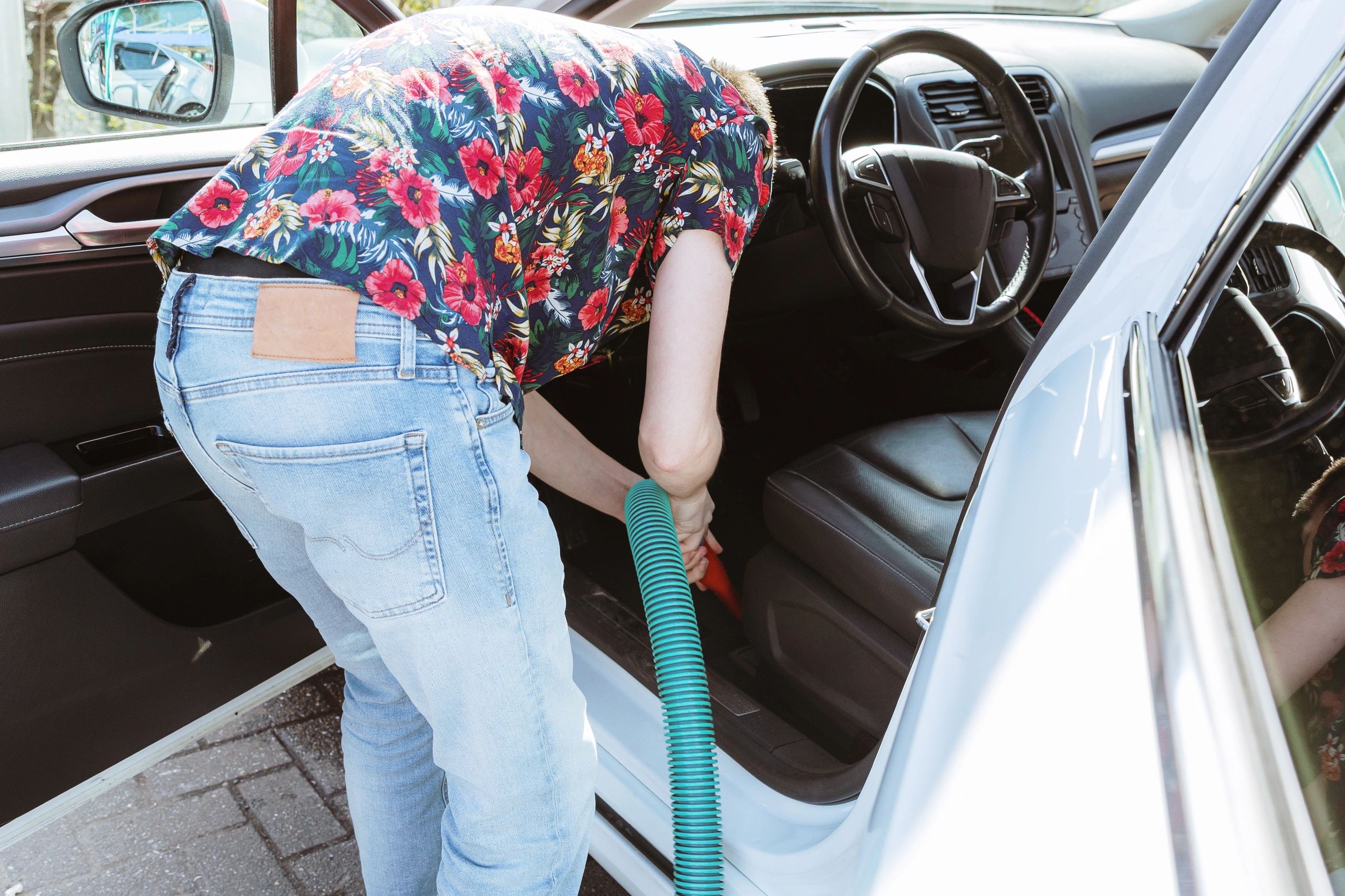 Technician vacuuming car interior seats and floor mats