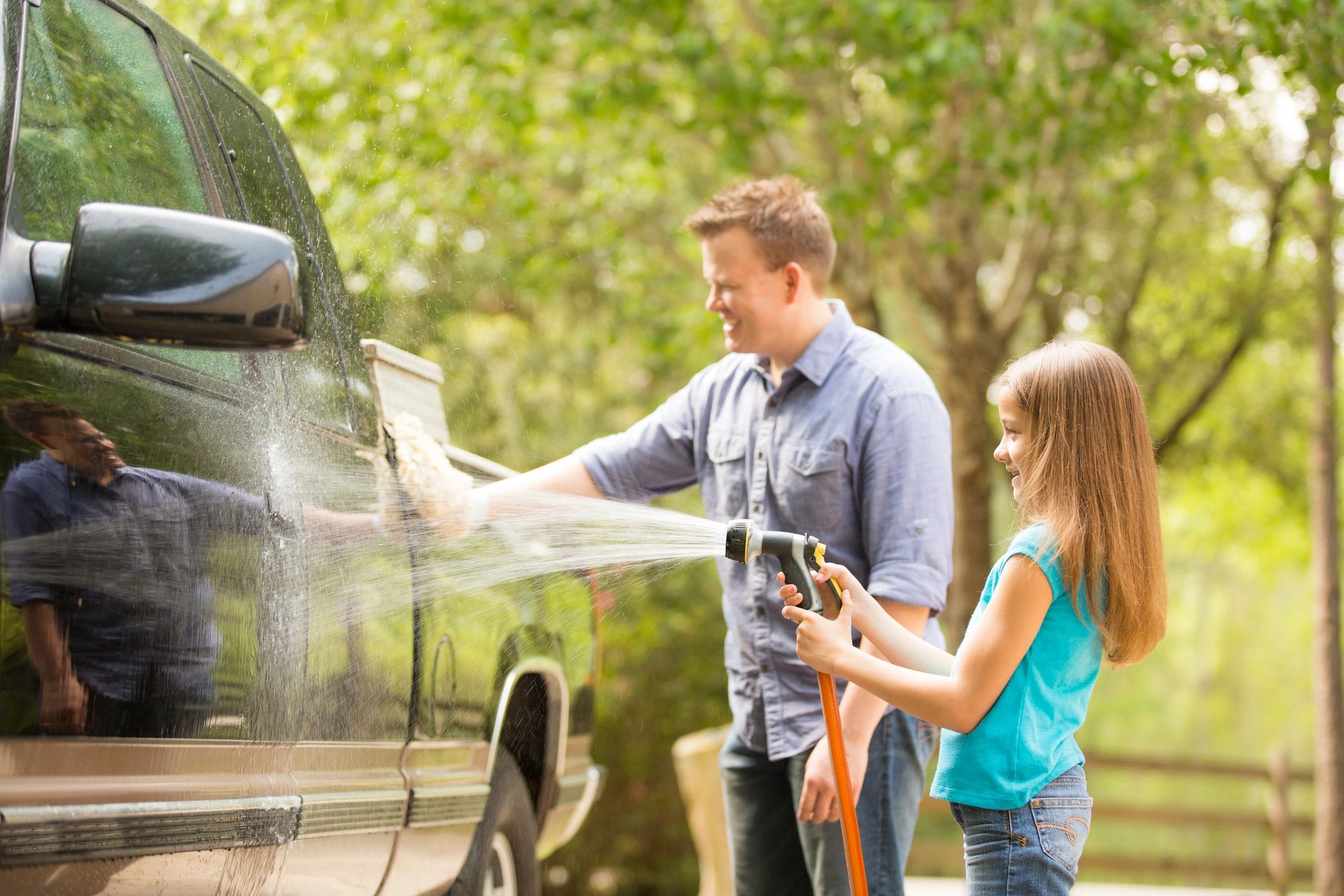 Father and daughter washing a car outdoors.